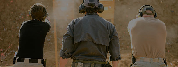 Three adults at shooting range, view from behind.